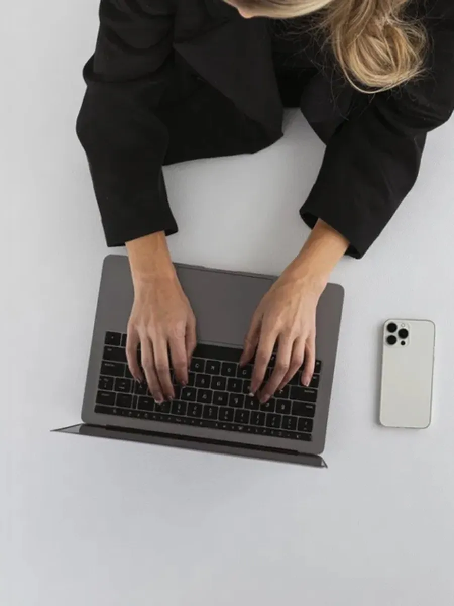 Thomas Uder Real Investments – Blick von oben auf eine Person, die am Laptop arbeitet, daneben ein Smartphone
